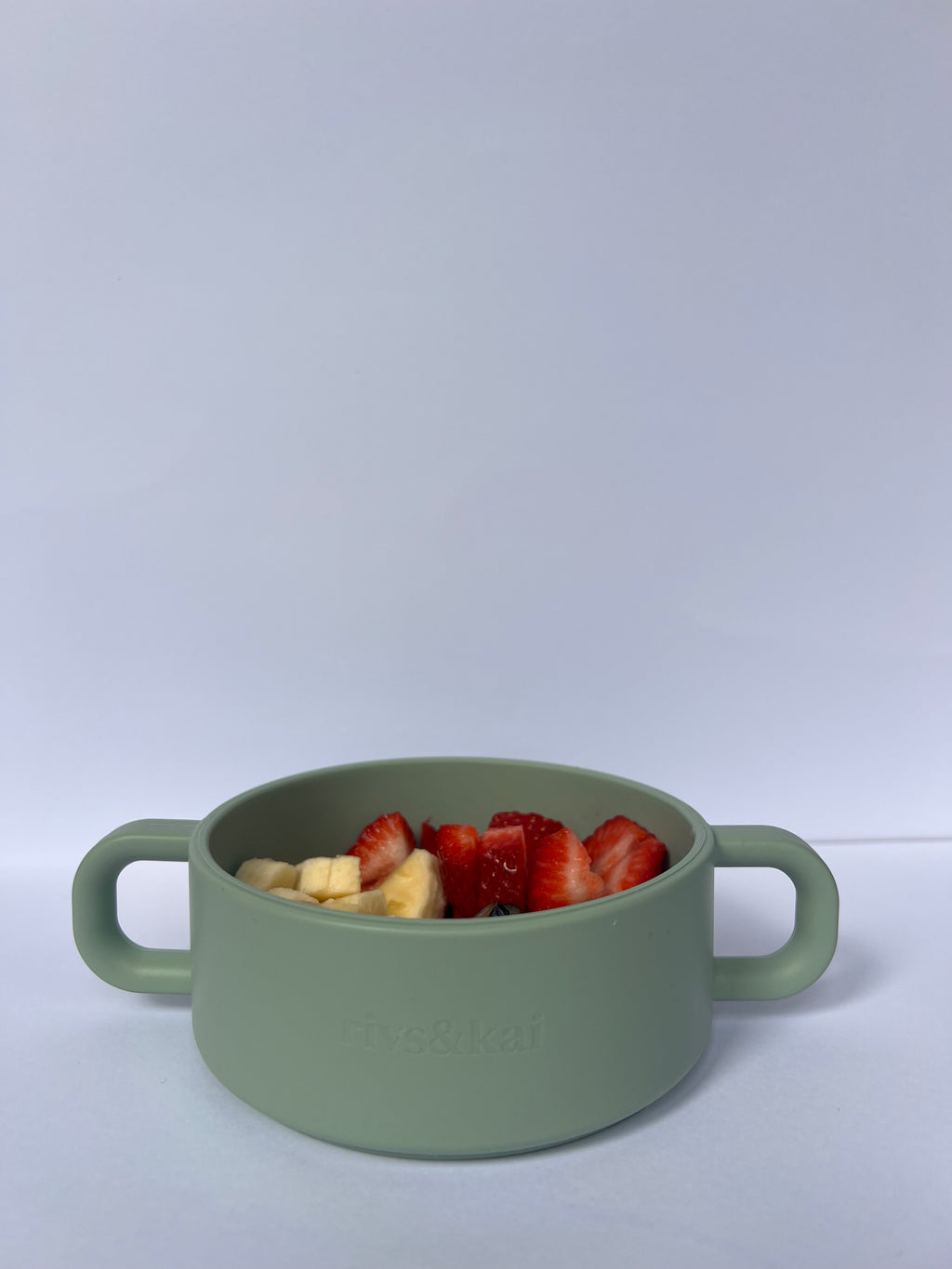 Green snack cup with strawberries and banana on a white background