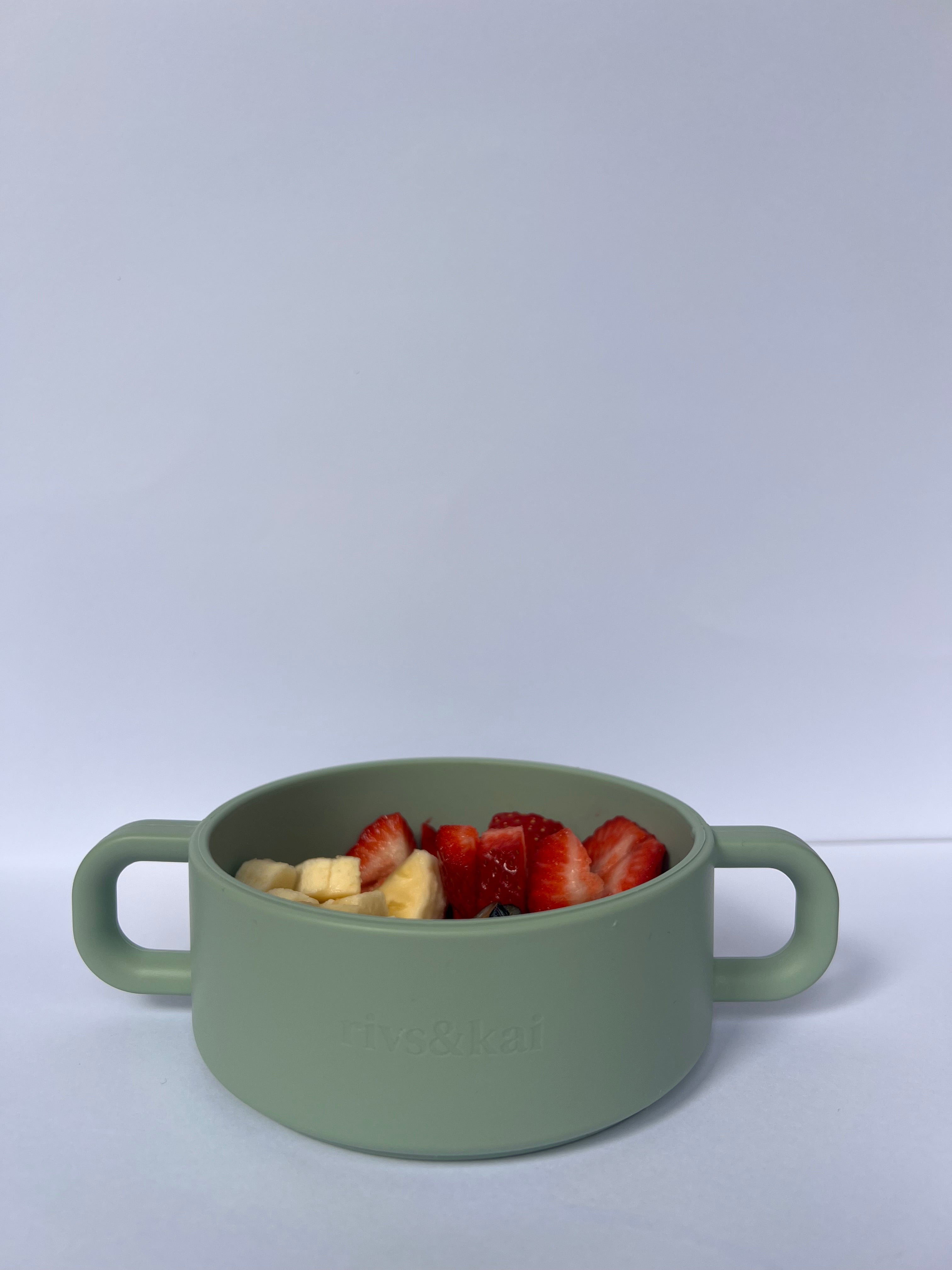 Green snack cup with strawberries and banana on a white background